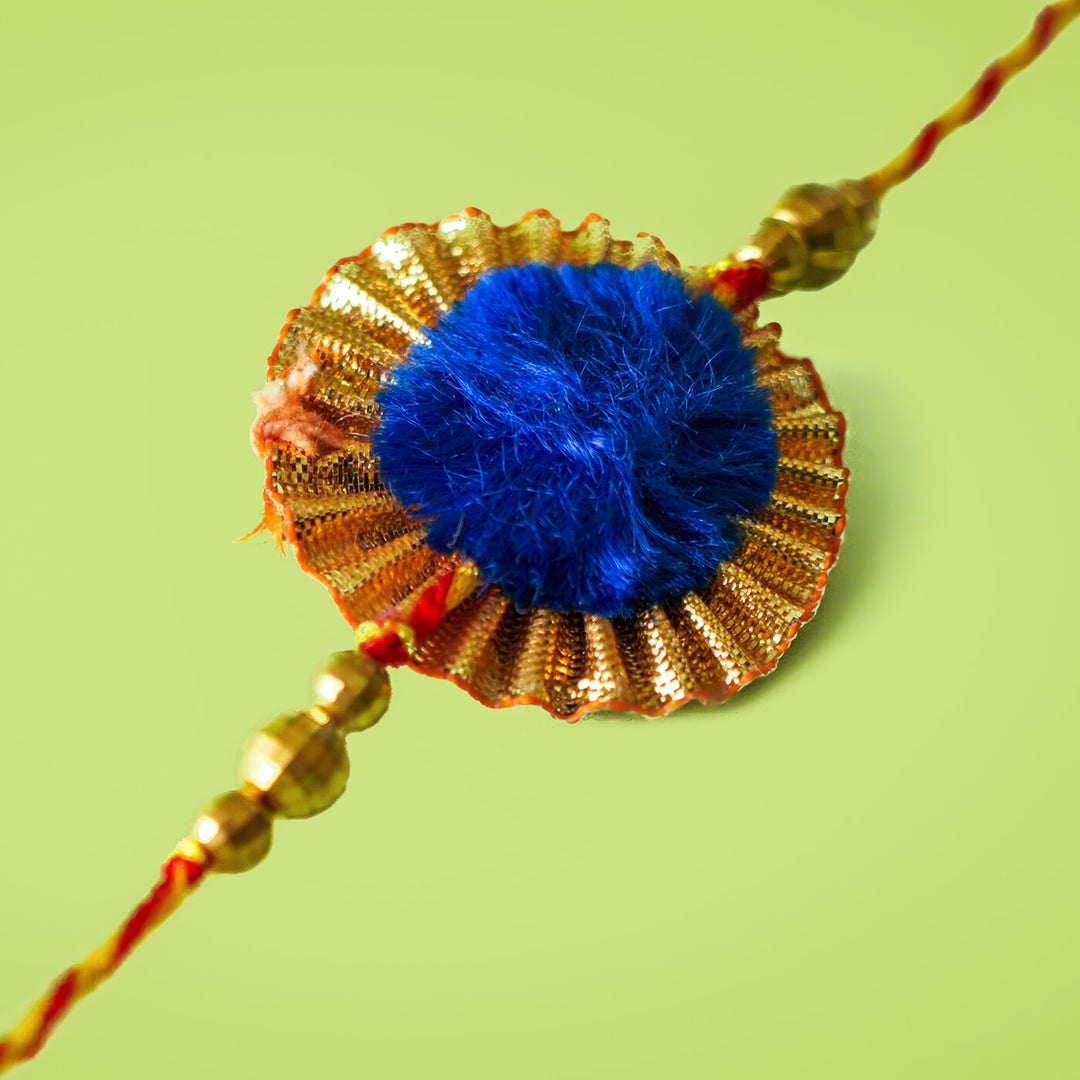 Ecofriendly Bamboo Rakhi With Golden Bead - Close-up of Blue Pom-Pom Rakhi