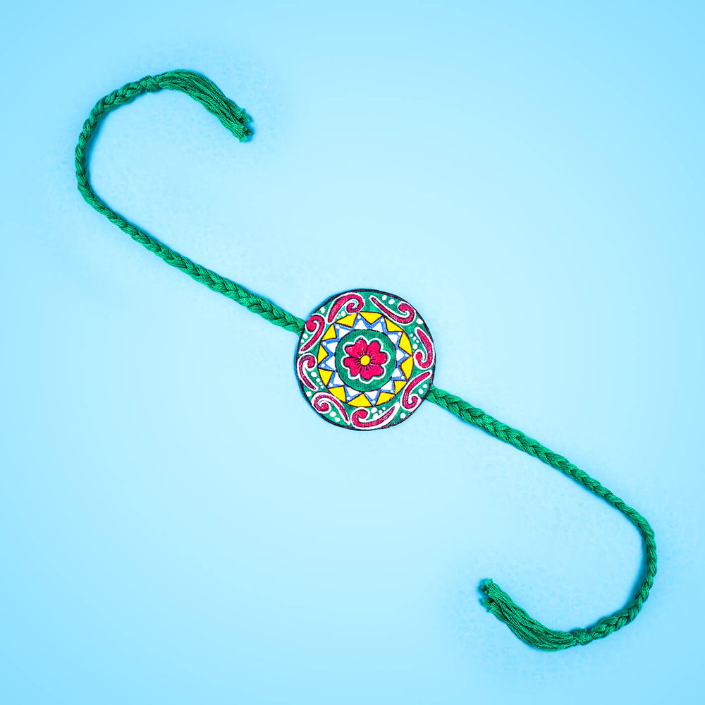 Hand Painted Seed Rakhi Green - Laid Flat on Blue Surface