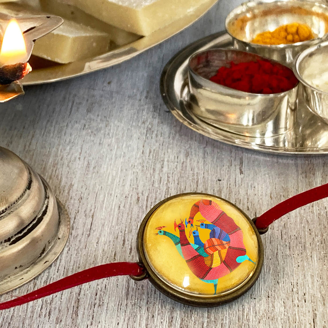 Gond Rooster Handcrafted Folkart Rakhi - Lifestyle View with Traditional Items