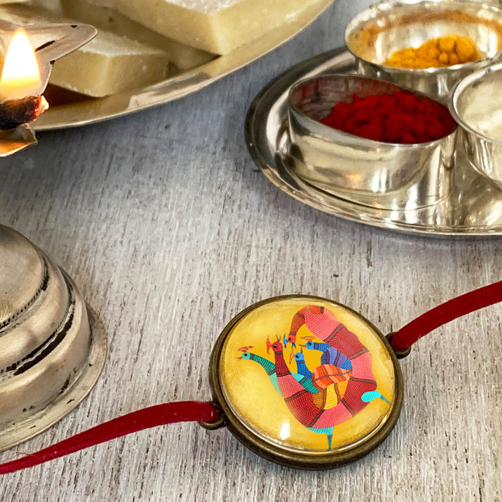 Gond Rooster Handcrafted Folkart Rakhi - Lifestyle View with Traditional Items