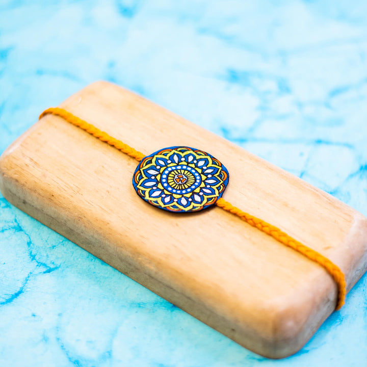 Hand Painted Seed Rakhi Orange - On Light Wooden Display Block