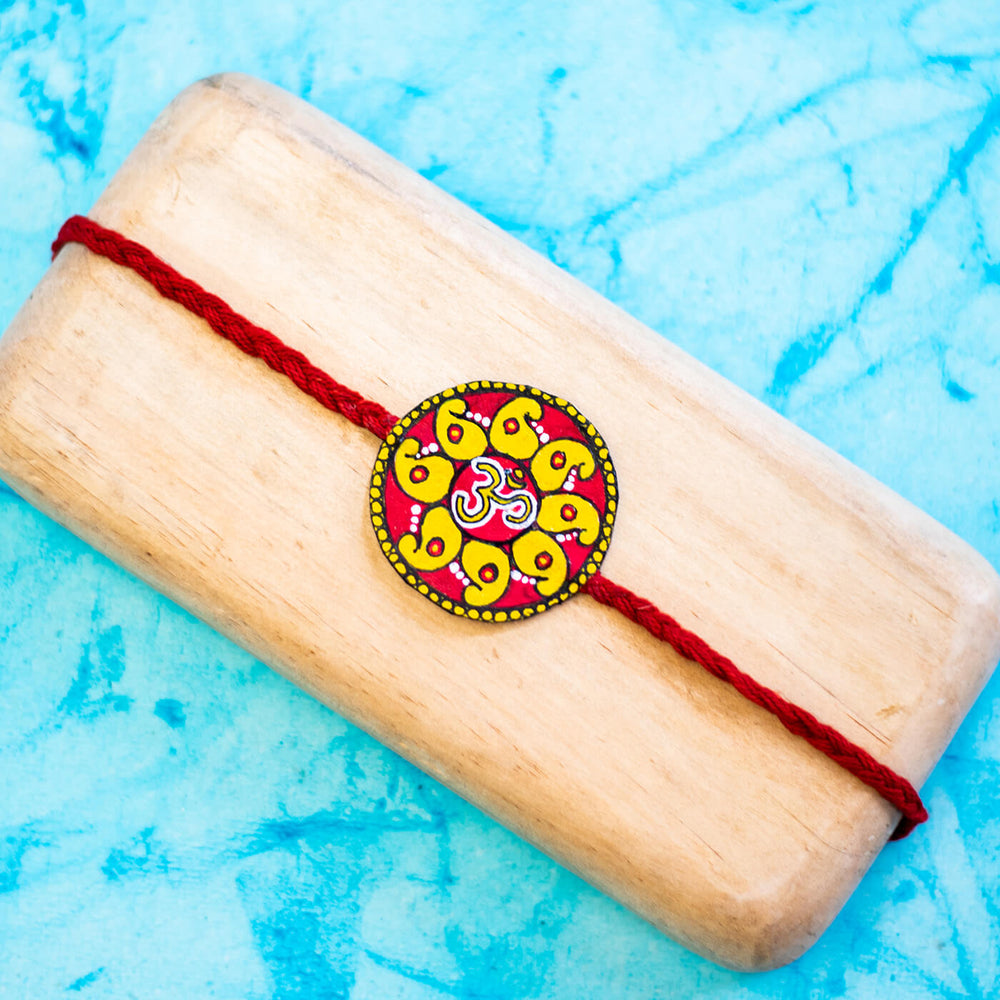 Hand Painted Seed Rakhi Red - Displayed on Wood Block