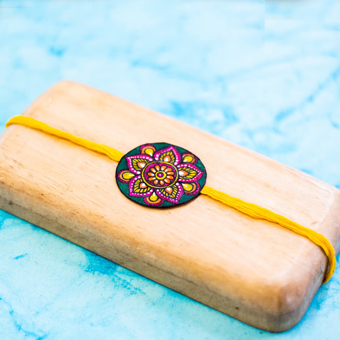 Hand Painted Seed Rakhi Yellow Unbraided - Close-up on Light Wood Tray